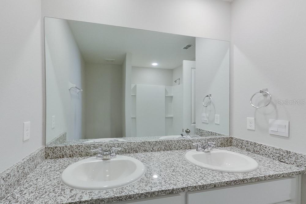 8731 Southwest 44th Court Ocala, FL 34476 - Photo 16 of 20 a bathroom with a granite countertop sink and a mirror