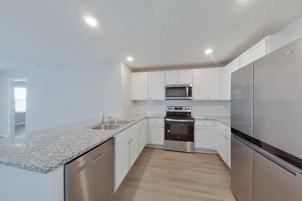 a kitchen with stainless steel appliances granite countertop a sink stove and refrigerator