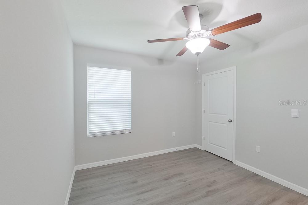 8731 Southwest 44th Court Ocala, FL 34476 - Photo 10 of 20 an empty room with wooden floor fan and windows