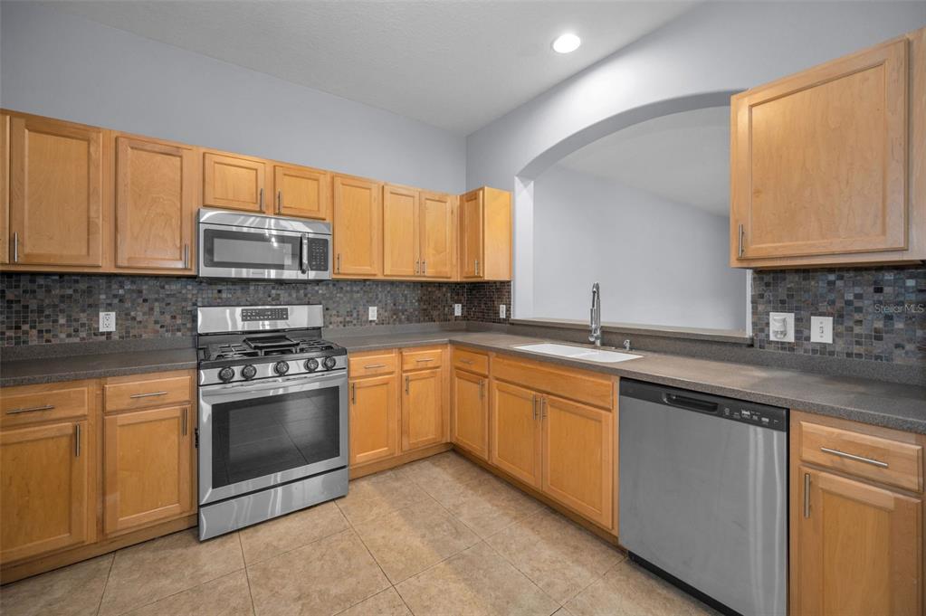 10125 Palladio Drive New Port Richey, FL 34655 - Photo 10 of 97 a kitchen with stainless steel appliances granite countertop a sink stove and microwave