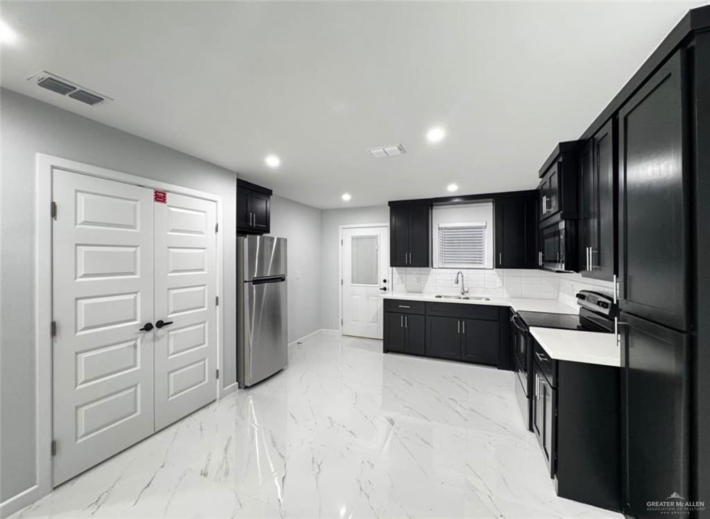 1604 Shadow Creek, Unit 1 Weslaco, TX 78596 - Photo 3 of 19 a large kitchen with a refrigerator and a sink