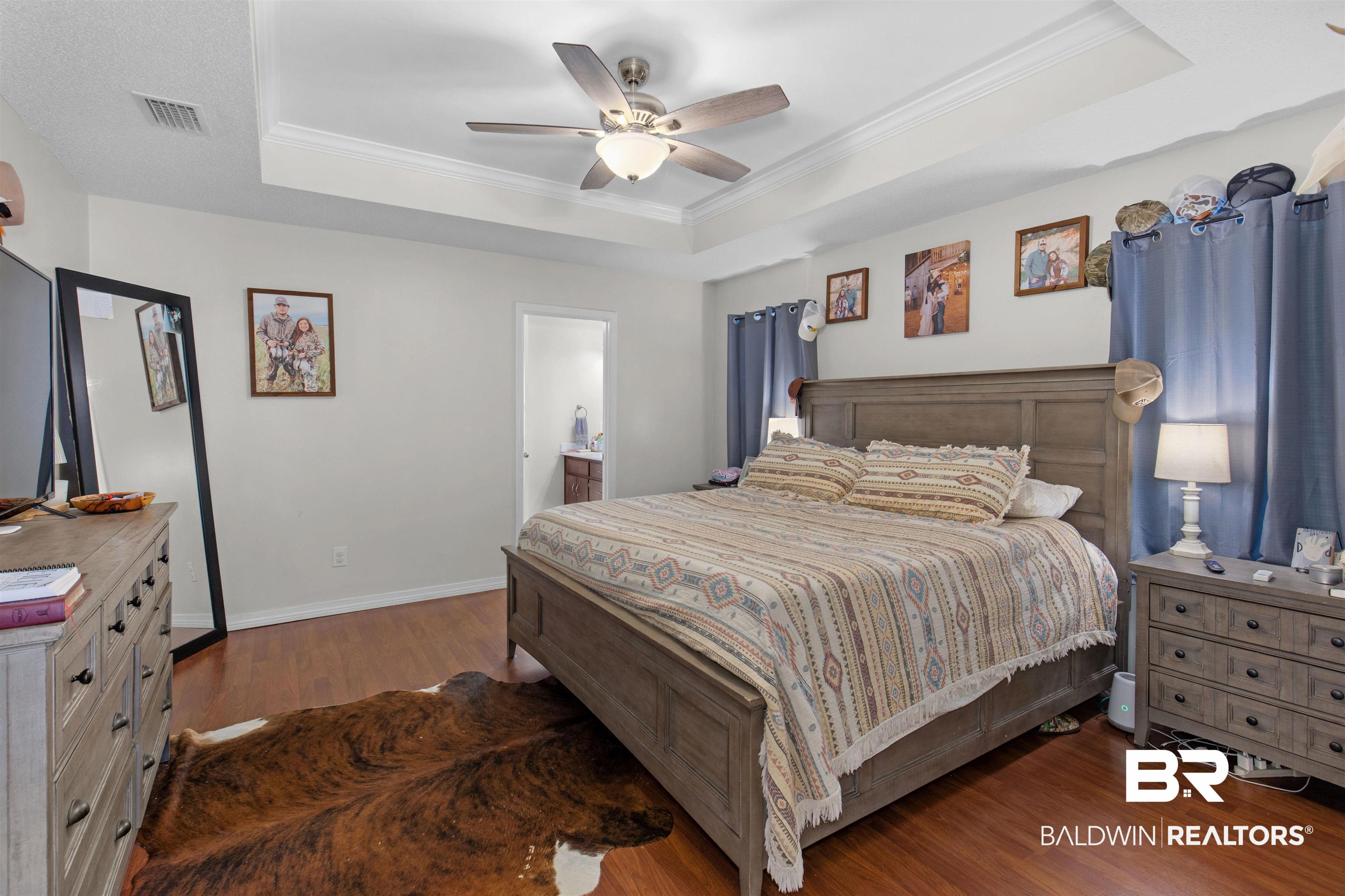 4950 Clealand Court Mobile, AL 36695 - Photo 9 of 20 Bedroom featuring wood finished floors, visible vents, baseboards, a tray ceiling, and crown molding