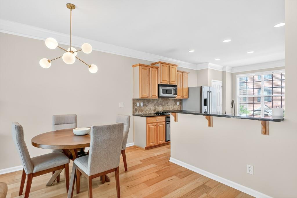 635 Coligny Court Atlanta, GA 30350 - Photo 11 of 31 a kitchen with stainless steel appliances granite countertop a stove a refrigerator a microwave a dining table and chairs with wooden floor