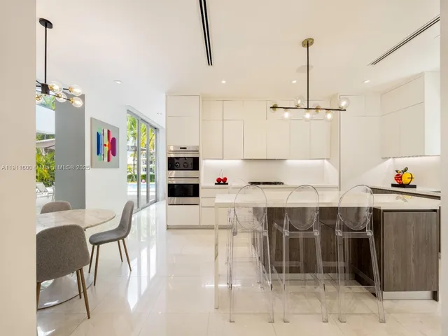a kitchen with stainless steel appliances kitchen island granite countertop a table and chairs in it