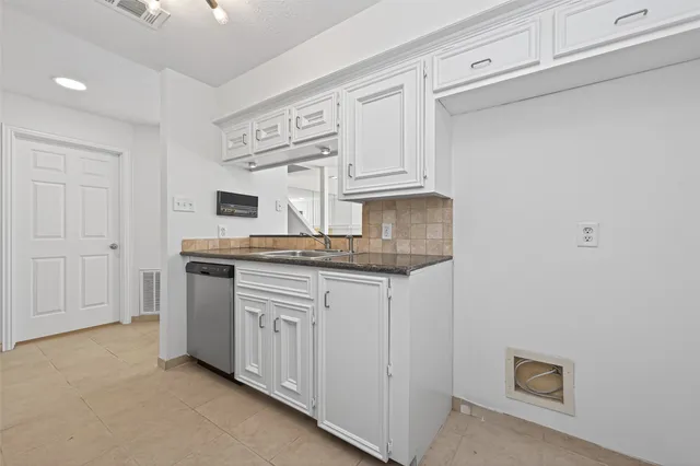 a kitchen with stainless steel appliances granite countertop a sink and a white cabinets