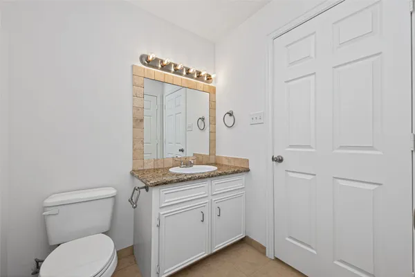 a bathroom with a granite countertop toilet a mirror and a sink