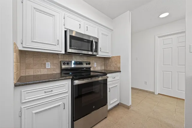 a kitchen with white cabinets and stainless steel appliances