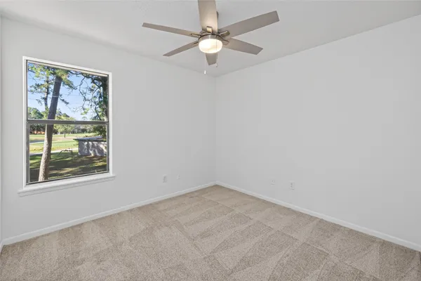 an empty room with windows and fan