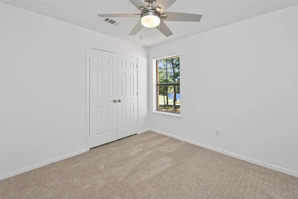 an empty room with windows and fan