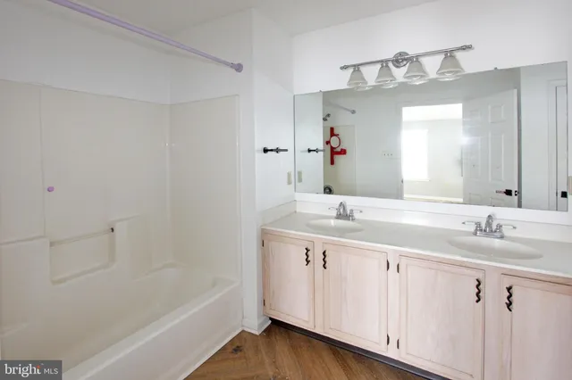 a bathroom with a double vanity sink a mirror and a bathtub