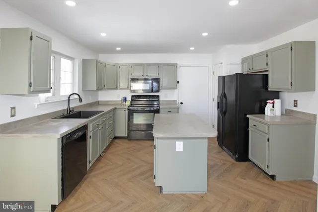 a kitchen with kitchen island a refrigerator sink and stove