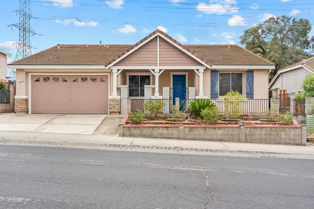 a front view of a house with a yard and potted plants
