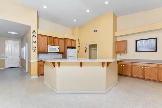 a large white kitchen with kitchen island a sink a stove and a refrigerator