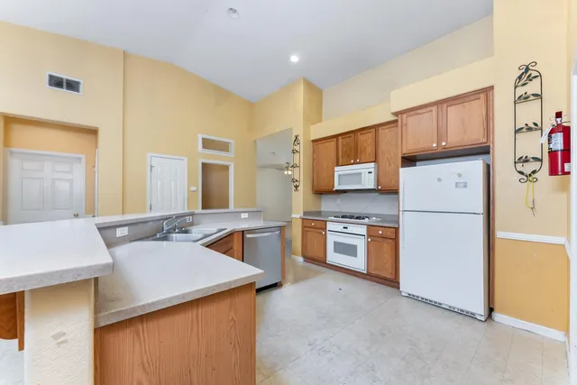 a kitchen that has a sink a stove top oven a refrigerator and a dining table