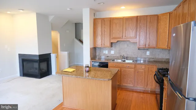 a kitchen with stainless steel appliances granite countertop a refrigerator a sink dishwasher and a stove