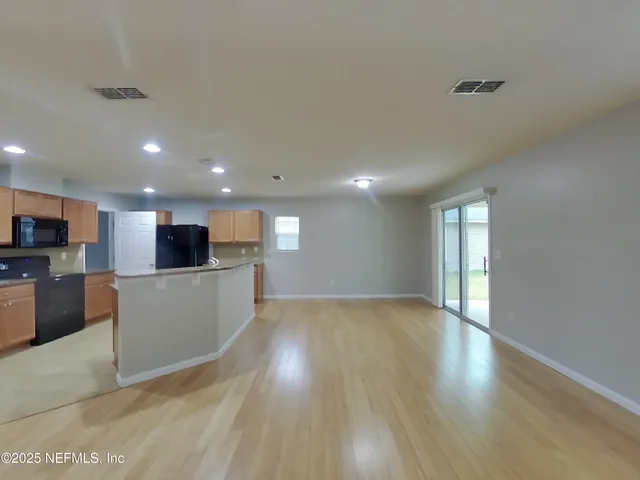 a view of kitchen with microwave a refrigerator and a stove top oven