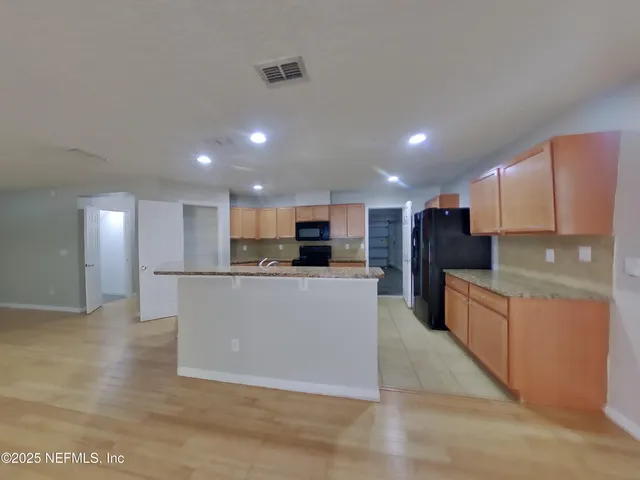 a large kitchen with stainless steel appliances kitchen island a large counter top and a stove top oven