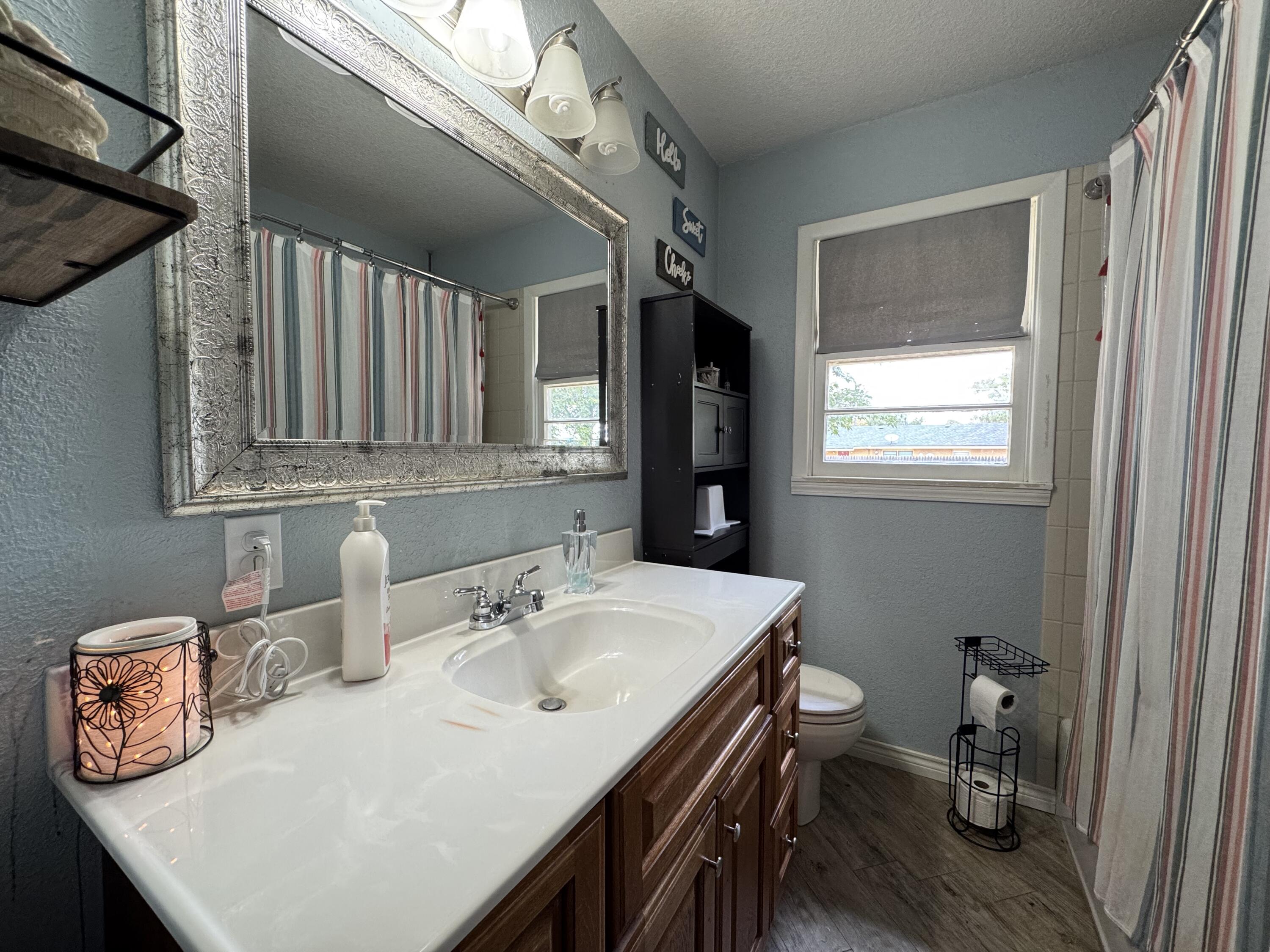3808 37th Street Lubbock, TX 79413 - Photo 5 of 19 a bathroom with a sink a toilet and a mirror