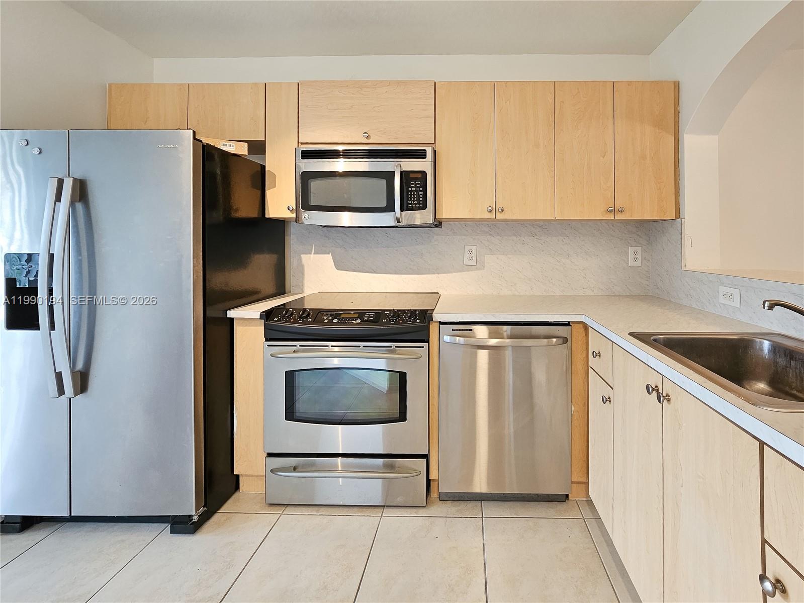 2651 Southeast 12th Road, Unit 105 Homestead, FL 33035 - Photo 2 of 24 a kitchen with stainless steel appliances a refrigerator sink and microwave