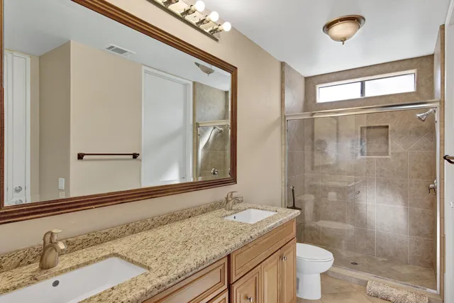 a bathroom with a granite countertop sink toilet a mirror and shower