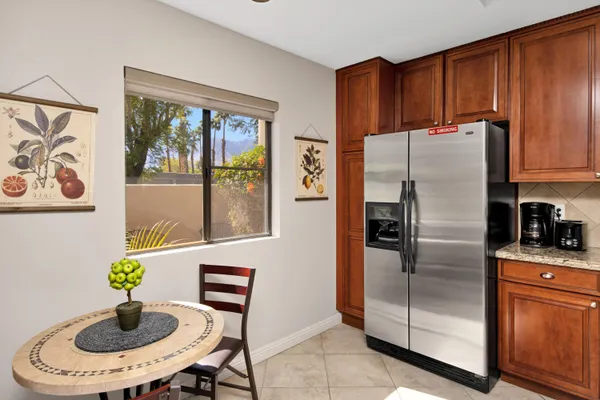 a kitchen with stainless steel appliances granite countertop a refrigerator a stove a sink a dining table and chairs with wooden floor