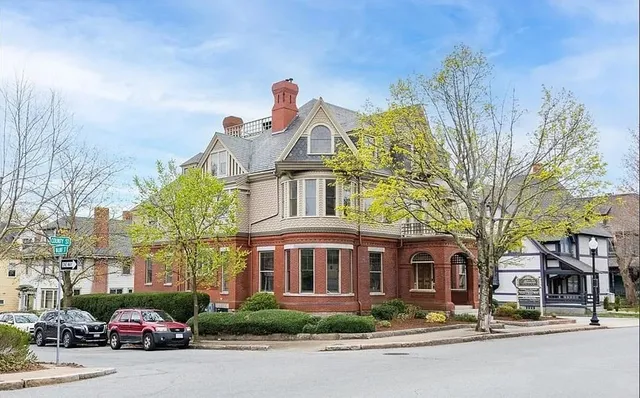 a front view of a building with lot of cars and trees