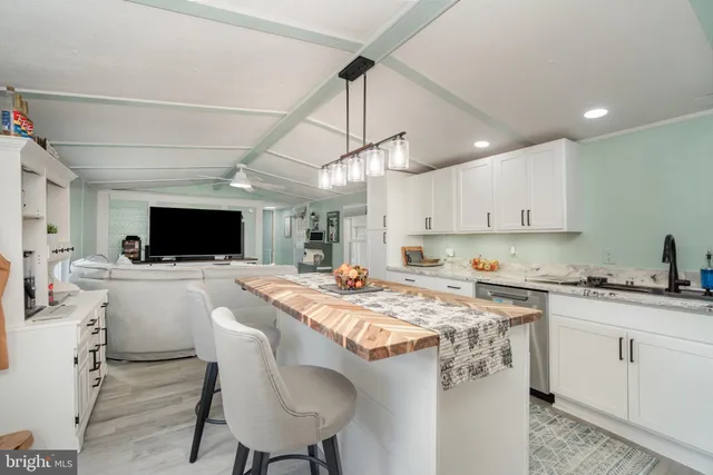 a kitchen with stainless steel appliances granite countertop a sink a stove a refrigerator and a dining table with wooden floor