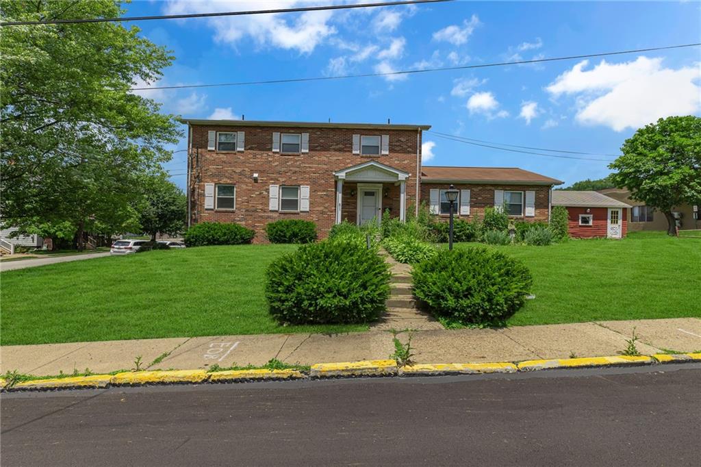 a view of a house with a yard and a large tree
