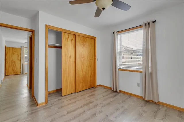an empty room with wooden floor cabinet and windows