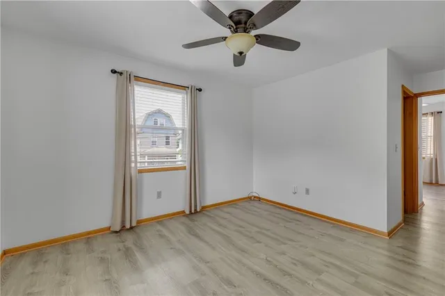 an empty room with wooden floor cabinet and windows