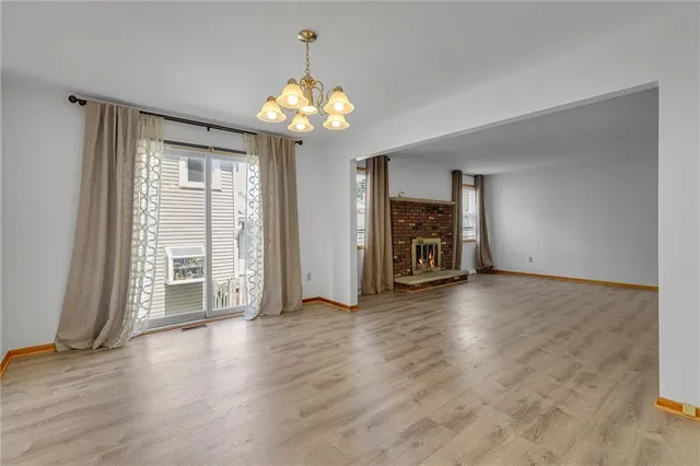 an empty room with wooden floor chandelier and windows