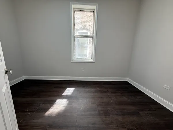 a view of a small space with wooden floor and large window