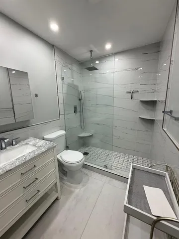 a bathroom with a granite countertop toilet a sink a mirror and shower