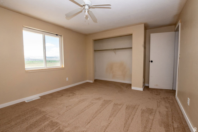 570 West Main Street Beaver, UT 84713 - Photo 18 of 43 Light brown carpet flooring with white baseboards, a window with exterior visibility, a built-in closet, and a ceiling fan