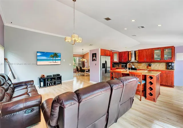 a kitchen with stainless steel appliances granite countertop a stove a sink dishwasher and a refrigerator with wooden floor