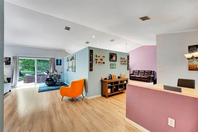 a dining room with wooden floor a chandelier a glass table and chairs