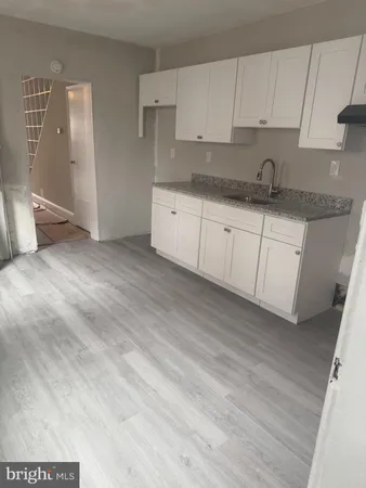 a kitchen with granite countertop a sink and white cabinets
