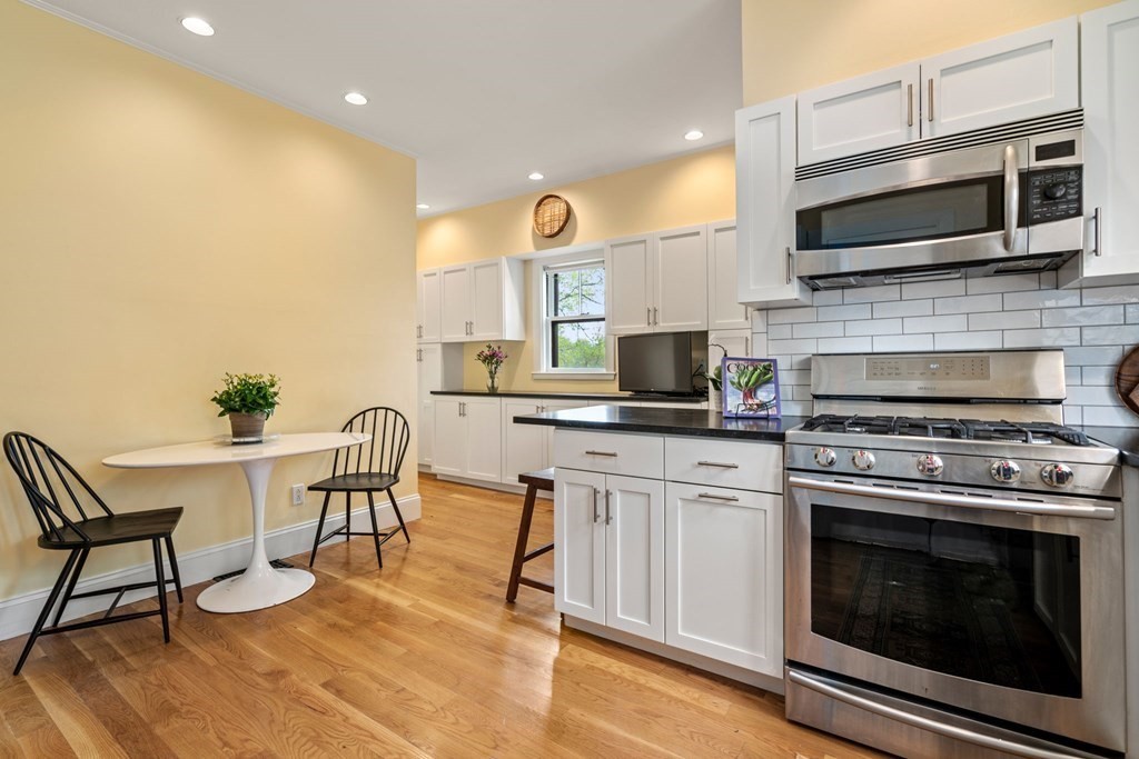 53 Oxford Road Newton, MA 02459 - Photo 13 of 32 a kitchen with a stove a microwave and white cabinets