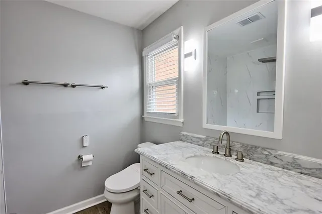 a bathroom with a granite countertop sink a toilet and a mirror