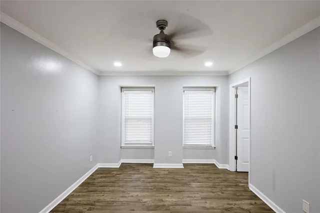a view of an empty room with wooden floor and fan