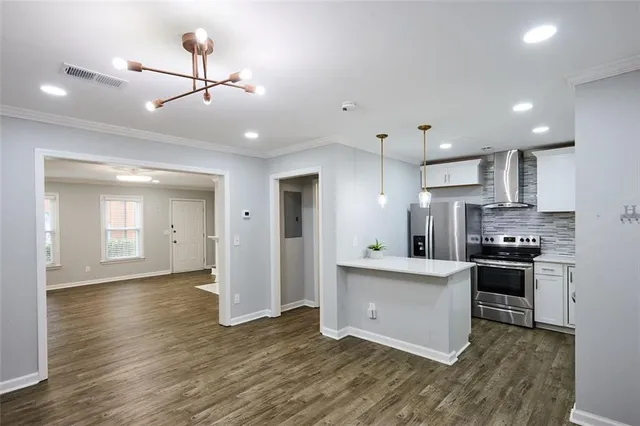 a kitchen with stainless steel appliances granite countertop a stove top oven a refrigerator a sink with island and chairs