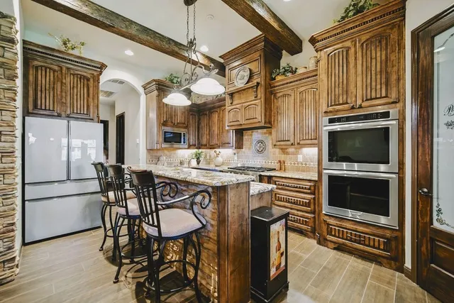 a kitchen with stainless steel appliances granite countertop a stove top oven a refrigerator a dining table and chairs with wooden floor