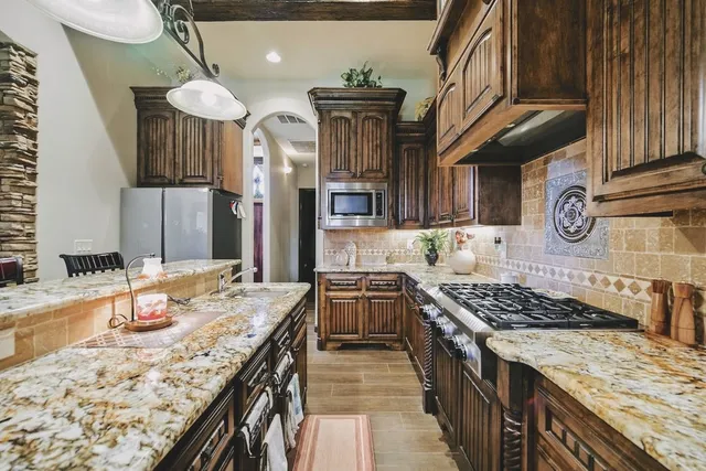 a kitchen with stainless steel appliances granite countertop a stove a sink dishwasher and cabinets with wooden floor