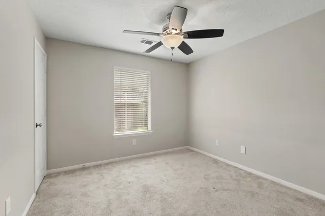 an empty room with a ceiling fan and window