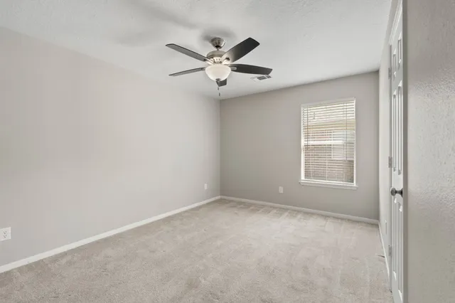 an empty room with windows and fan