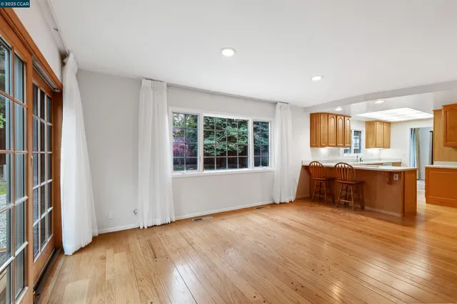 a living room with stainless steel appliances kitchen island granite countertop wooden floors and a large window