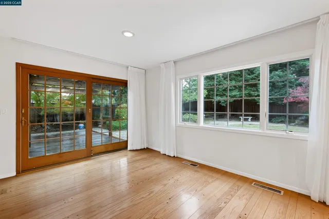 a view of empty room with wooden floor and fan