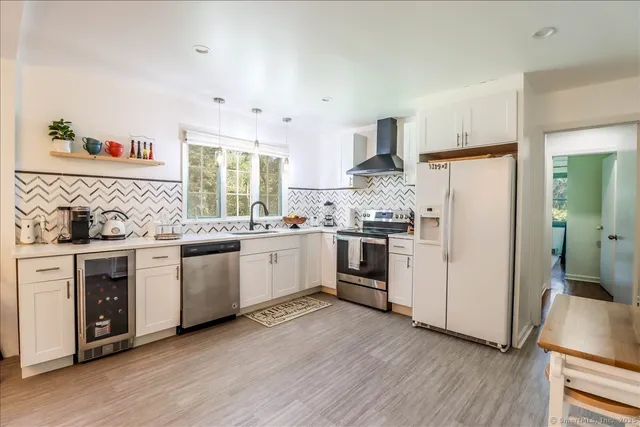 a open dining room with granite countertop a stove a sink a dining table and chairs with wooden floor