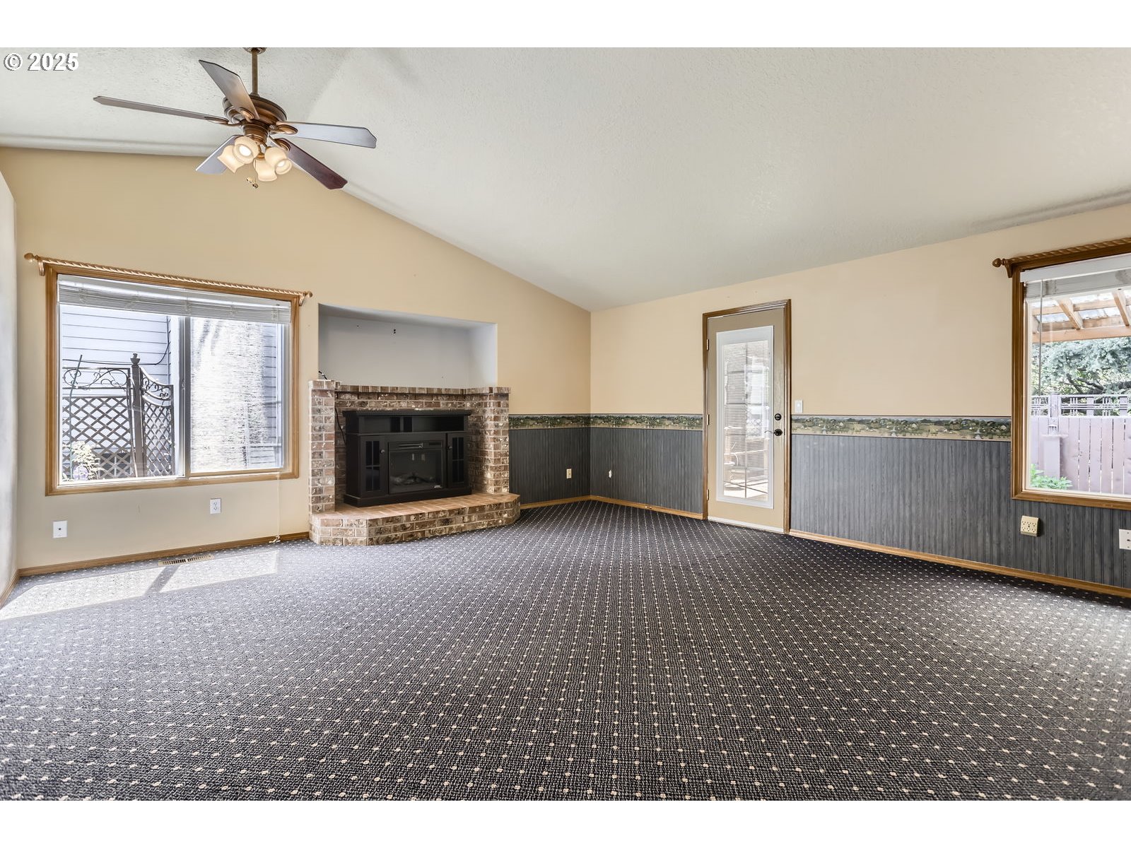 257 Southwest Nancy Circle Gresham, OR 97030 - Photo 13 of 36 a view of a livingroom with a fireplace a ceiling fan and windows