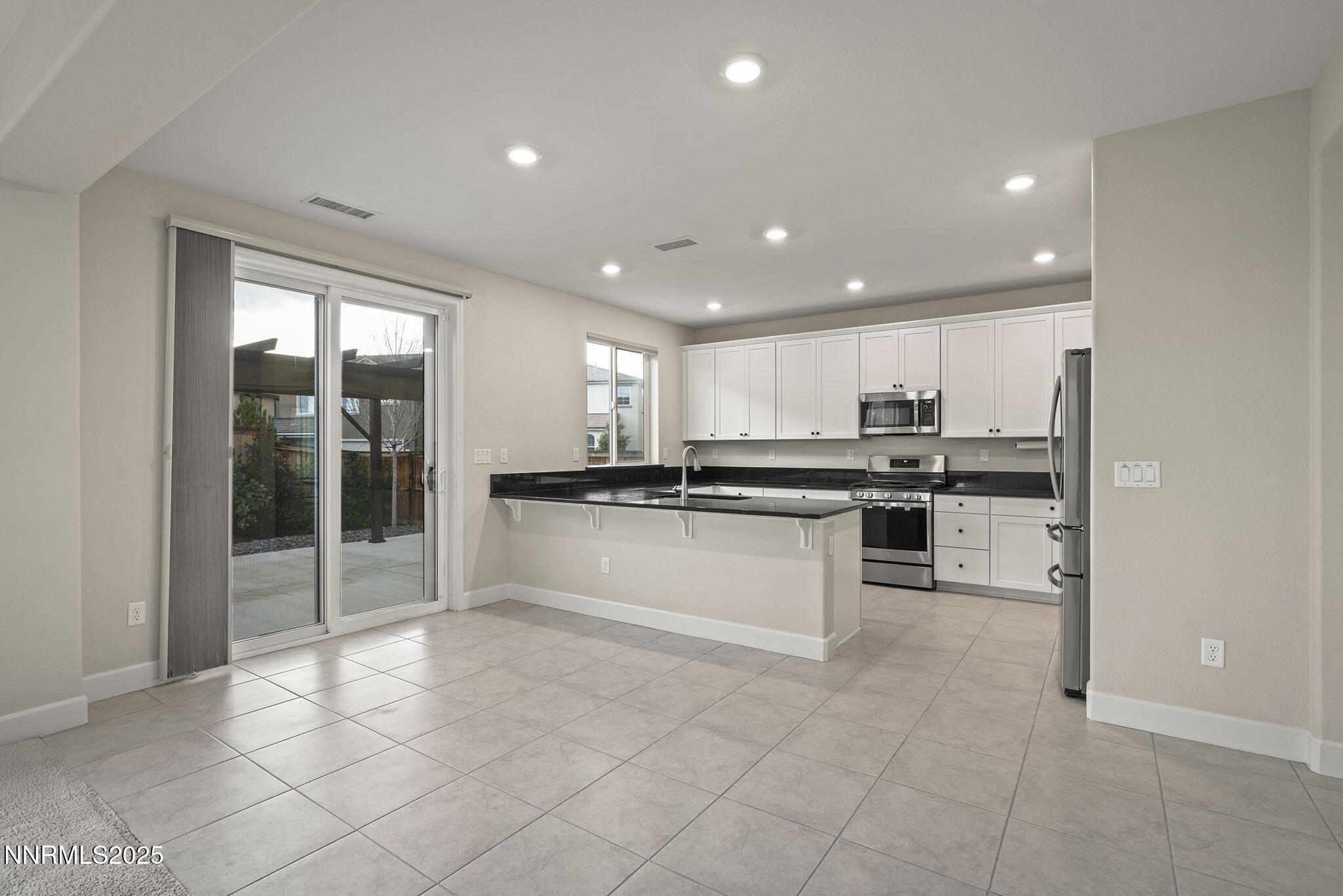 1119 Roswell Road Sparks, NV 89436 - Photo 3 of 35 a large kitchen with kitchen island a stove a sink a refrigerator and white cabinets with wooden floor